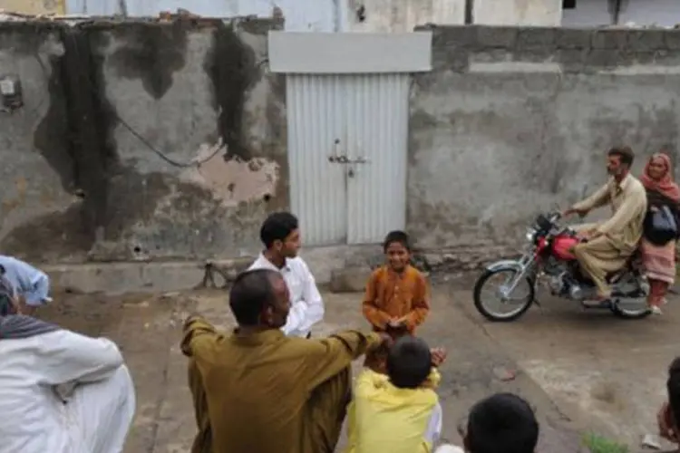 
	Paquistaneses se re&uacute;nem em frente &agrave; casa da menina crist&atilde; acusada de blasf&ecirc;mia: ela foi presa na quinta-feira passada e colocada em deten&ccedil;&atilde;o provis&oacute;ria por 14 dias
 (Aamir Qureshi/AFP)