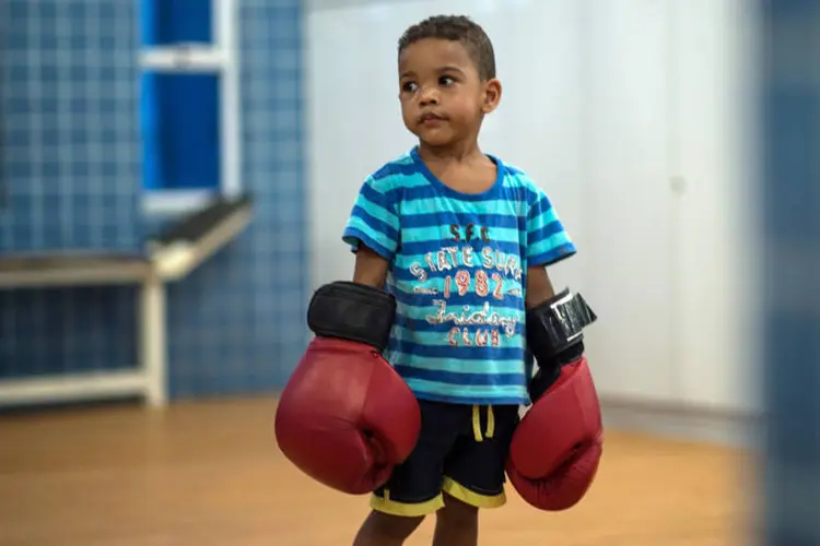 
	Menino aprende boxe em ONG na favela da Mar&eacute;: ensinar um esporte violento pode, inicialmente, parecer uma forma estranha de formar cidad&atilde;os-modelo
 (Christophe Simon / AFP)