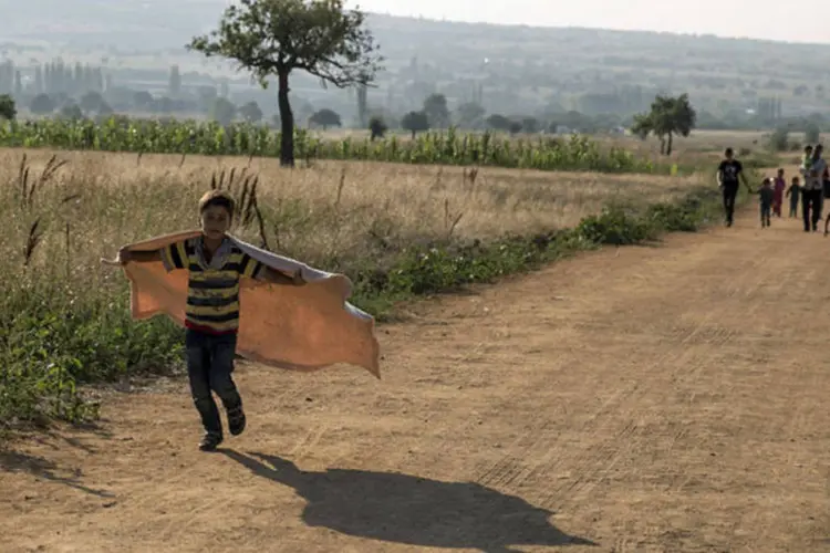 
	Em busca de paz: refugiados caminham em uma vila perto da cidade de Presevo, na S&eacute;rvia, em agosto de 2015 .
 (REUTERS)