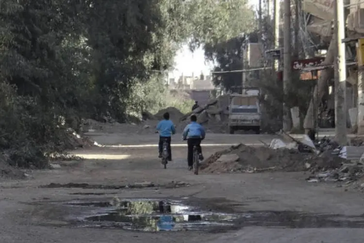 Meninos andam de bicicleta em meio a casas destruídas no leste da Síria: violência armada obrigou 2,8 milhões de crianças a largarem a escola (Mohamed al-Khalif/AFP)