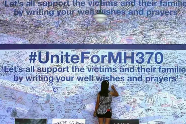 Mulher escreve uma mensagem para os passageiros a bordo do avião desaparecido da Malaysia Airlines e seus familiares, em Petaling Jaya (Samsul Said/Reuters)