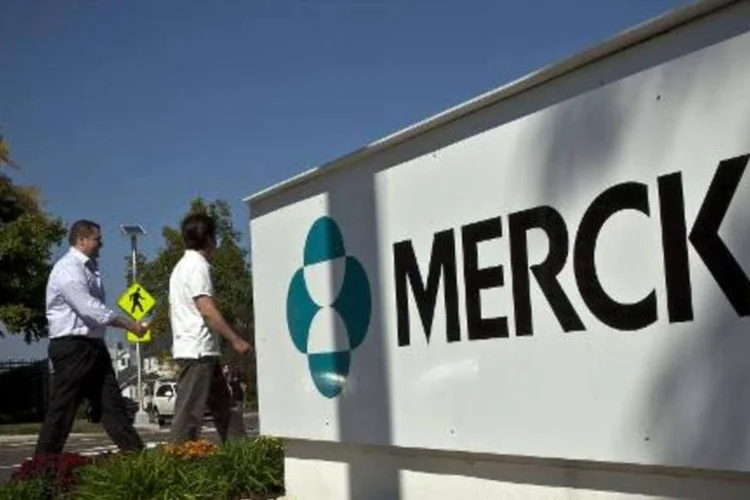 Funcionários da Merck passam ao lado de placa da empresa nos EUA (Kena Betancur/AFP)