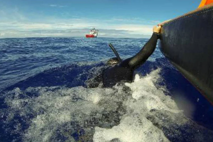 Mergulhador ao lado de embarcação que busca caixa-preta: quando suposta zona de imersão dos destroços da aeronave for localizada, robô submarino equipado com sonar será enviado (AUSTRALIAN DEFENCE/AFP)