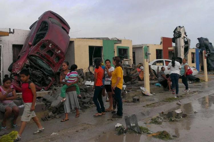 Moradores saem à rua, enquanto carros arrastados por um tornado são vistos numa rua em Ciudad Acuna, no México (REUTERS/Ramiro Gomez)