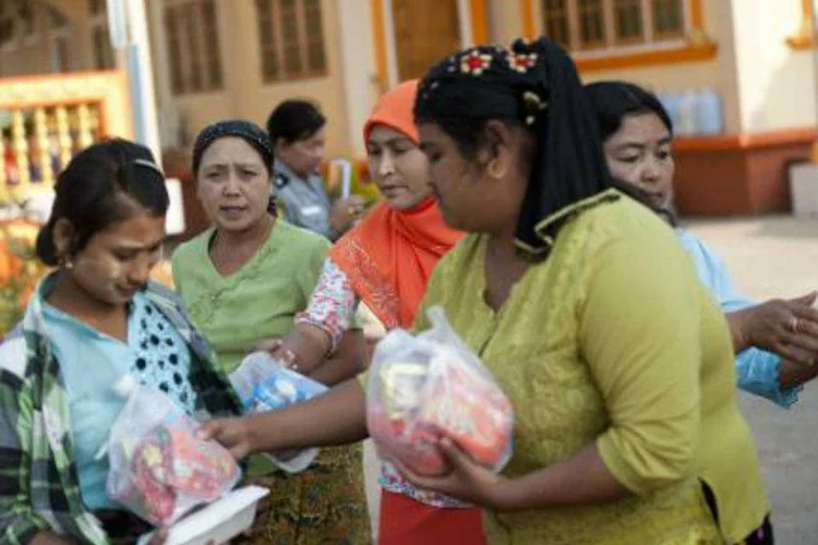 Moradores que fugiram de áreas de conflito na fronteira com a China recebem comida, em um abrigo para refugiados improvisado em um mosteiro da cidade birmanesa de Lashi (AFP/ Ye Aung Thu)