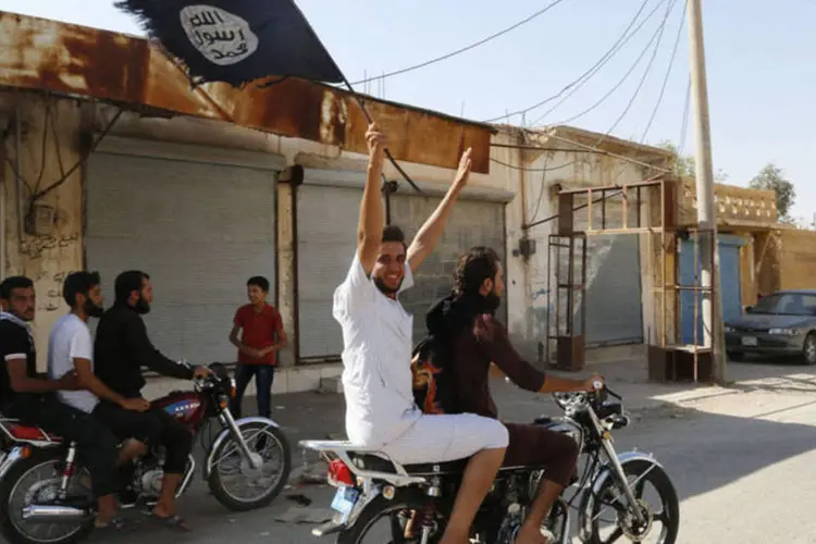 Morador de Tabqa com a bandeira do grupo Estado Islâmico, perto da cidade de Raqqa, na Síria (Reuters)