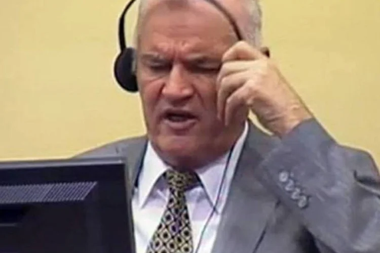 Na imagem reproduzida da TV, Ratko Mladic retira os fones de ouvido antes de ser retirado da sala de audiências (AFP)
