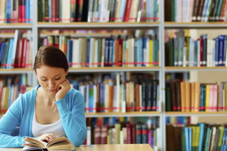 moça lendo em biblioteca (Thinkstock)