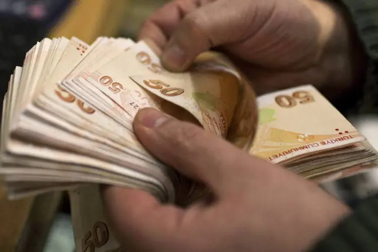 Homem contando notas de 50 liras turcas em uma casa de câmbio de Istambul, na Turquia (Kerim Okten/Bloomberg)