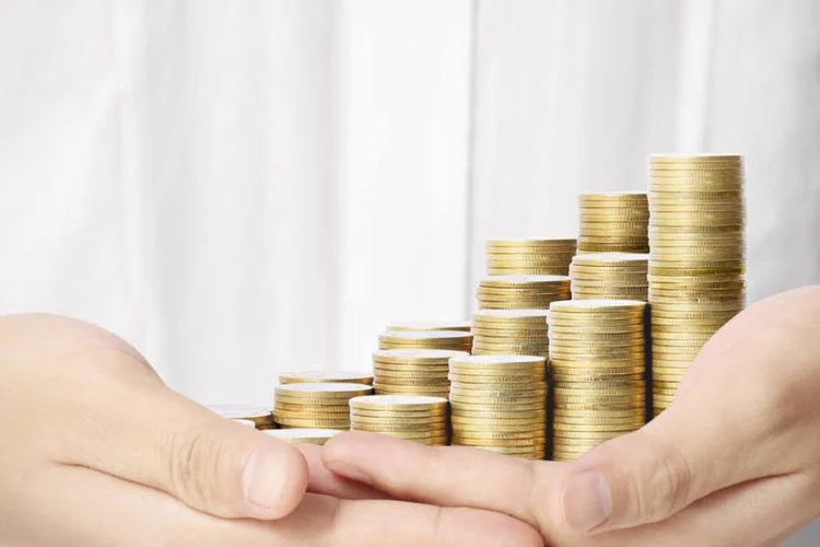 Homem segura moedas (Thinkstock/denphumi)