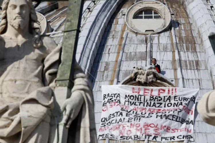 
	O empres&aacute;rio Marcello Di Finizio, na c&uacute;pula da Bas&iacute;lica de S&atilde;o Pedro, segura uma faixa que diz: &quot;Socorro! Basta Monti, basta Europa, basta multinacionais!&quot;
 (Alessandro Bianchi/Reuters)
