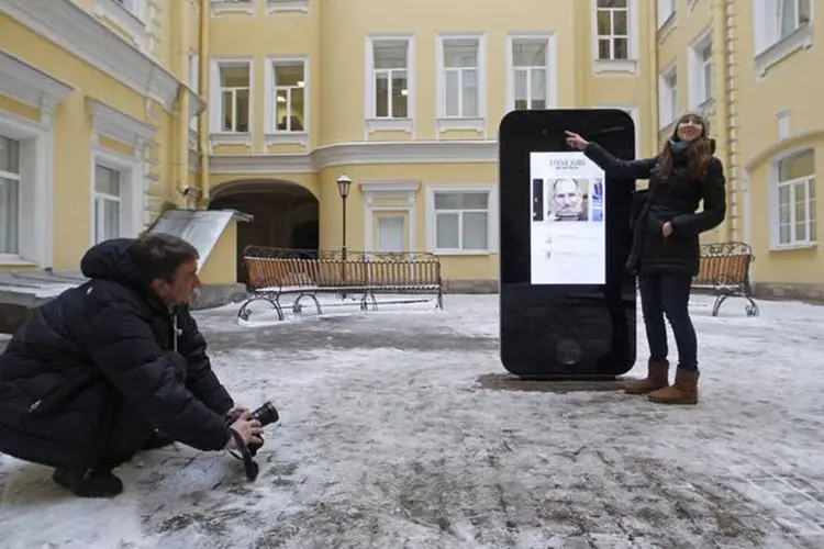 Homem tira foto de monumento em forma de iPhone para homenagear o fundador da Apple Steve Jobs em São Petersburgo (Alexander Demianchuk/Reuters)