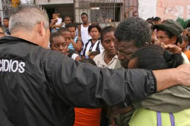 Funcionários do Departamento de Homicídios do Panamá consolam um casal que perdeu o filho em um tiroteio, na Cidade do Panamá (Teresita Chavarria/AFP)
