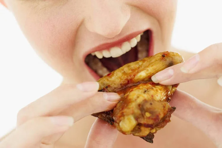 
	Mulher come asinha de frango: 1,3 bilh&atilde;o de asinhas de frango ser&atilde;o consumidas durante o Super Bowl
 (Thinkstock)