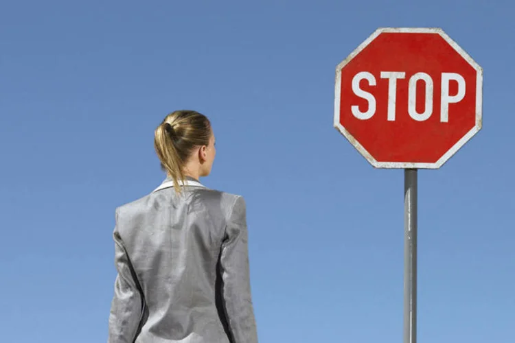 Mulher em frente a sinal de pare: elas são mais qualificadas mas não chegam no topo (Thinkstock)