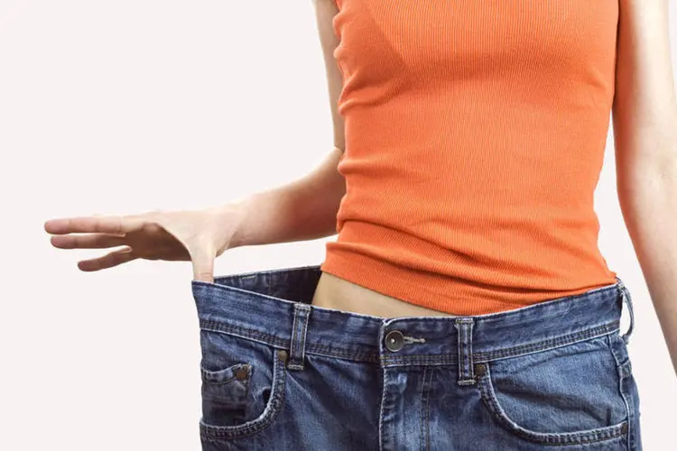 Mulher segura calças largas após dieta (Thinkstock)