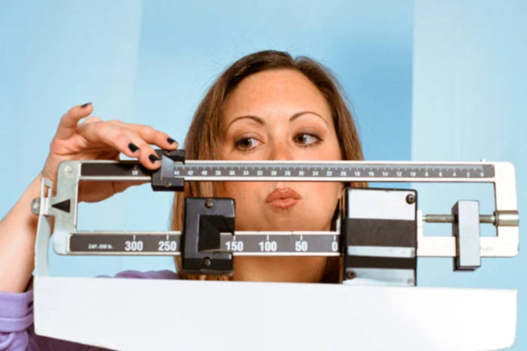 Mulher se pesando na balança (ThinkStock)
