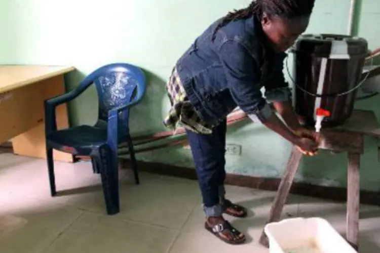 Mulher lava mãos para prevenir-se contra Ebola: OMS revisou para 887 número de mortos pelo vírus (AFP)