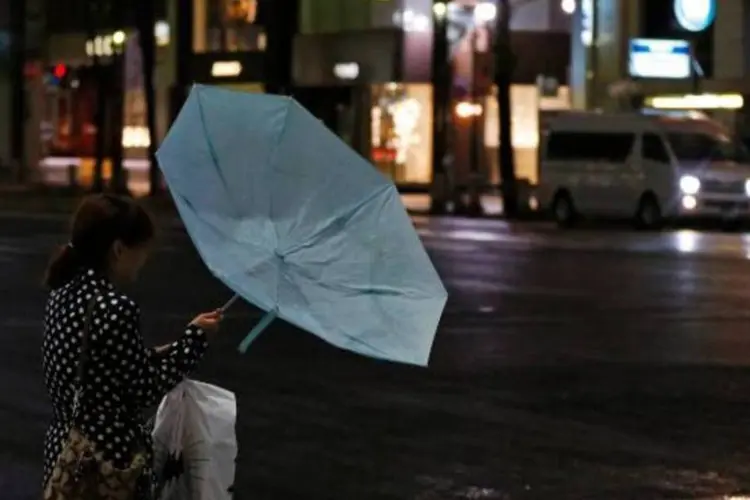 Mulher segura guarda-chuva com a chegada de ventos fortes em Tóquio, ameaçada pelo tufão Jelawat (Toru Hanai/Reuters)