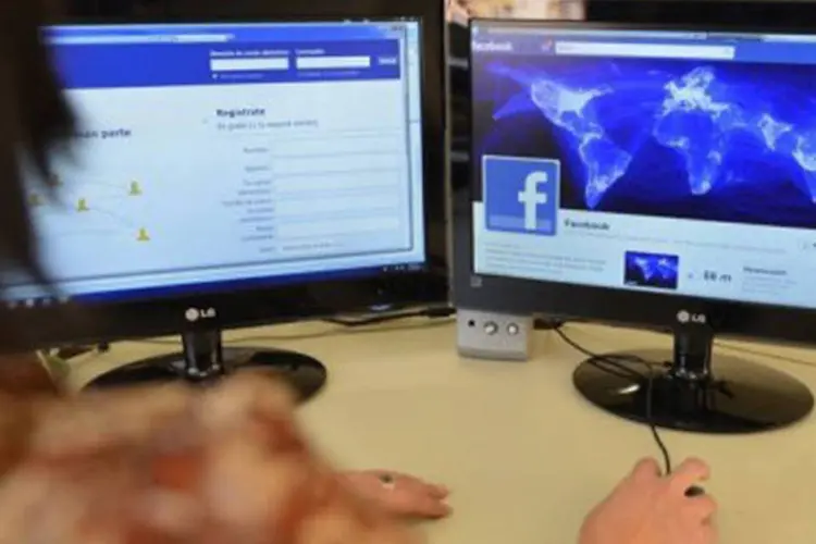 Mulher visita página do Facebook em dois computadores (Rodrigo Buendia/AFP)