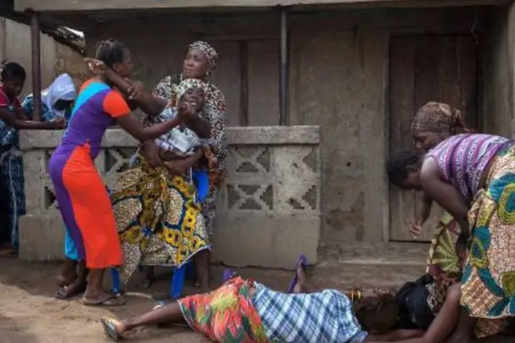 Mulheres passam mal ao saber que vizinha morreu vítima de ebola, em Waterloo, Serra Leoa (Florian Plaucheur/AFP)