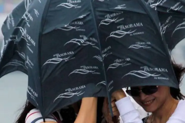 Mulheres se protegem com guarda-chuva durante a chegada do tufão "Vicente" em Hong Kong (Tyrone Siu/Reuters)
