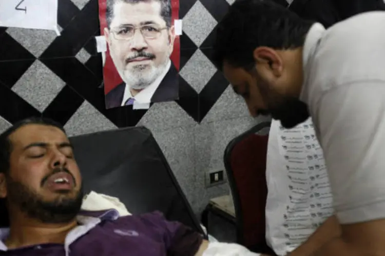 Apoiador do presidente deposto do Egito, Mohammed Mursi, recebe atendimento médico após confrnto que deixou dezenas de mortos em frente à sede da Guarda Republicana no Cairo (REUTERS/Amr Abdallah Dalsh)