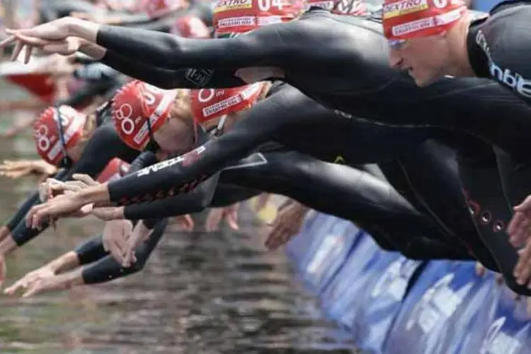 Praticantes de triatlo mergulham no mar: amadores devem dedicar , no mínimo, uma hora por dia para prática do esporte (Getty Images)