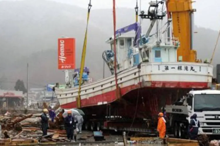 Homens fazem a limpeza dos estragos provocados pelo tsunami: barcos "progressivamente soltarão combustíveis no mar" (Toshifumi Kitamura/AFP)