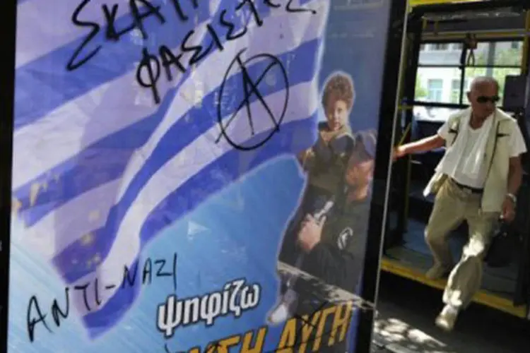 
	Cartaz do partido de extrema direita Chryssi Avghi &eacute; pichado em ponto de &ocirc;nibus de Atenas: as agress&otilde;es racistas no pa&iacute;s aumentaram de modo exponencial
 (Louisa Gouliamaki/AFP)