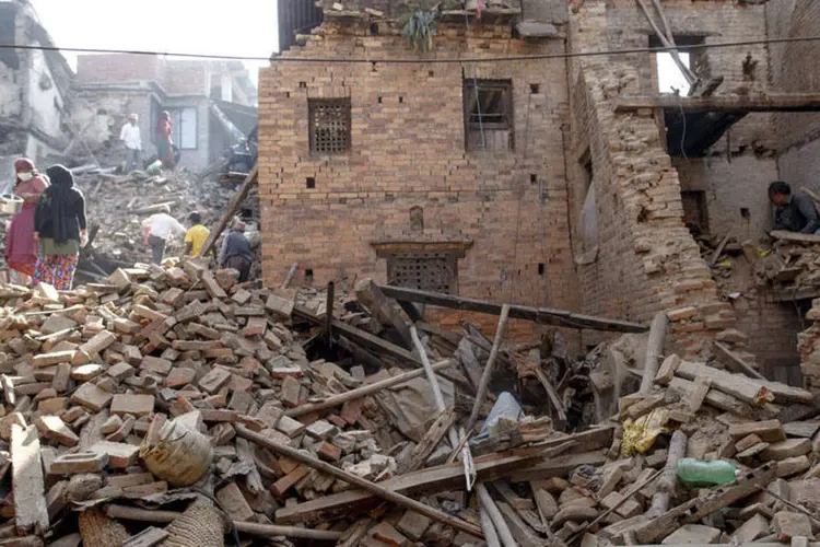 
	Moradores sobre destro&ccedil;os no Nepal: mais de 200 mil im&oacute;veis foram destru&iacute;dos e outros 190 mil danificados
 (REUTERS/Athit Perawongmetha)