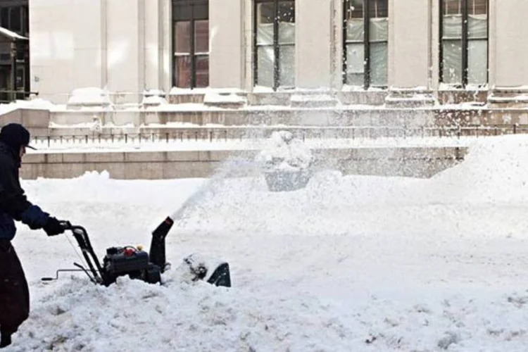Homem abre passagem na neve de Nova York com máquina de triturar gelo (Andrew Burton/Getty Images)