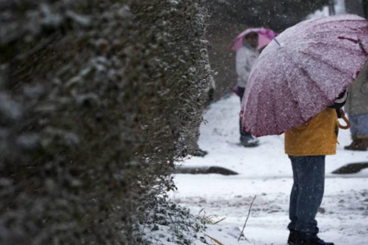 Homem segura guarda-chuva coberto de neve em rua de Washington, nos Estados Unidos (REUTERS/Shannon Stapleton)