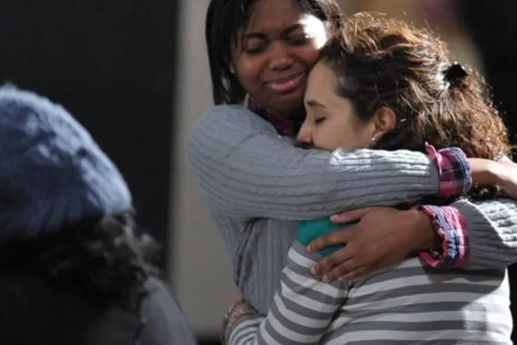 Duas jovens se abraçam em cerimônia dedicada às vítimas do tiroteio em escola, no dia 16 de dezembro de 2012, em Newtown, Connecticut
 (Mandel Ngan/AFP)