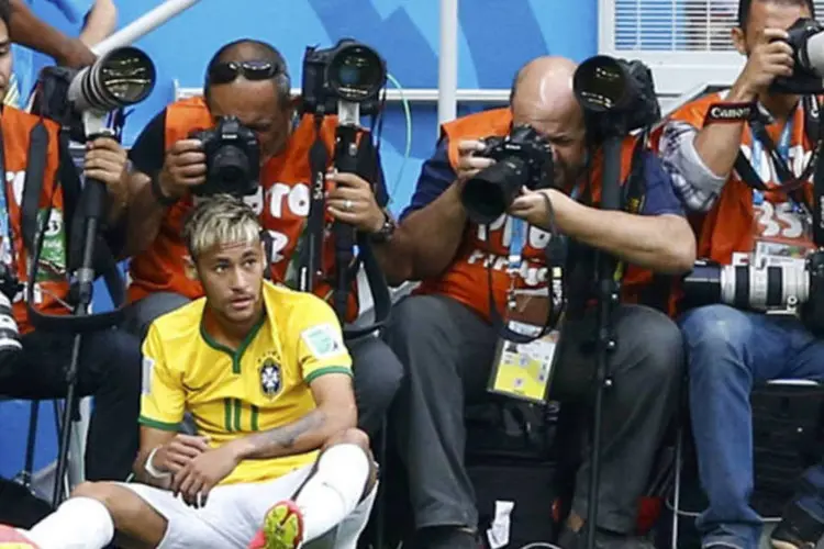 Neymar sentado em frente aos fotógrafos, após ser empurrado na partida Brasil X Camarões (Dominic Ebenbichler / Reuters)