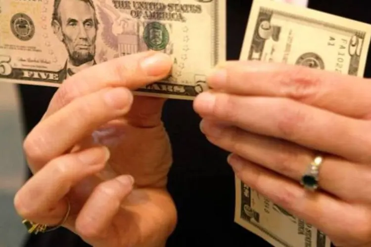 Notas de dólar sendo manuseadas (Alex Wong/Getty Images)