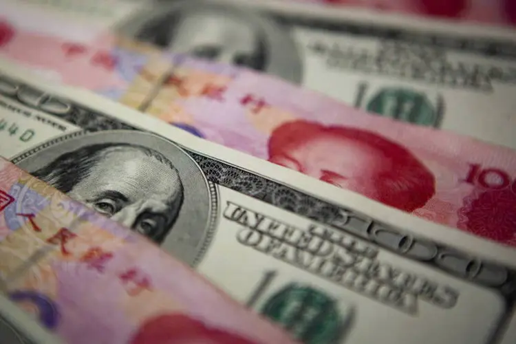 
	Notas de Yuan e de D&oacute;lares: O Banco do Povo da China (PBoC, o BC chin&ecirc;s) estipulou a taxa de paridade de hoje em 6,1133 yuans por d&oacute;lar
 (Nelson Ching/Bloomberg)