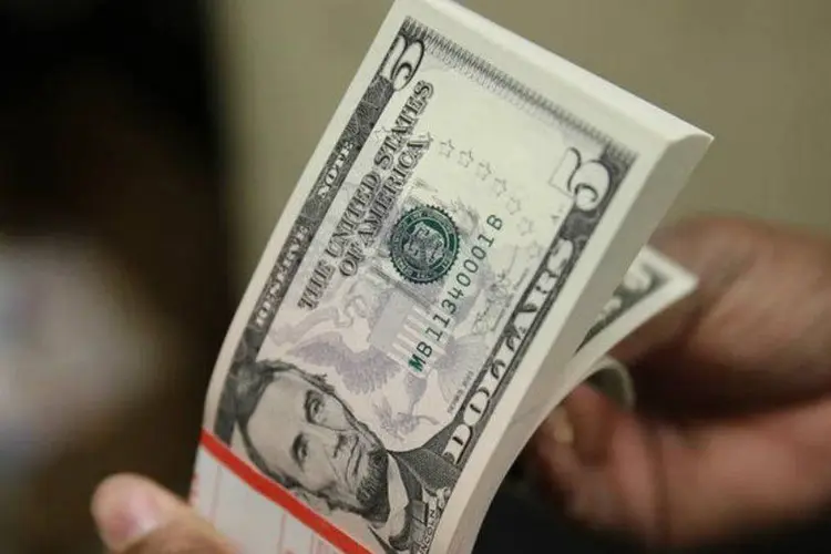 
	Pessoa conta notas de d&oacute;lar: &agrave;s 12h16, a moeda norte-americana tinha queda de 0,30 por cento, a 2,9128 reais na venda
 (Gary Cameron/Reuters)
