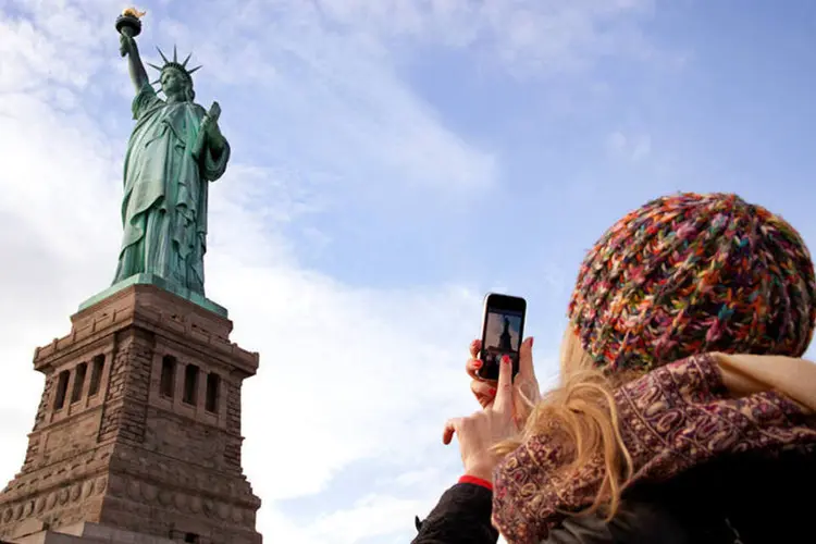 
	Turista fotografa Est&aacute;tua da Liberdade, em Nova York: foram 56,4 milh&otilde;es de visitantes em 2014
 (decisiveimages/Thinkstock)