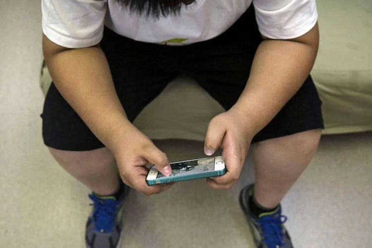 
	Crian&ccedil;a obesa mexendo no telefone
 (Getty Images)