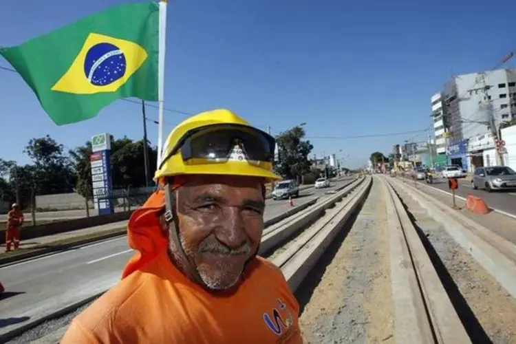 Trabalhador posa com bandeira do Brasil em linha de VLT sendo construída em Cuiabá (Eric Gaillard/Reuters)
