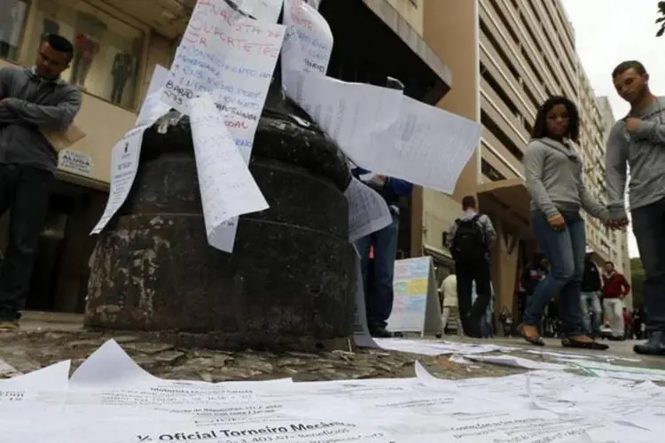 Pessoas olham para papeis com ofertas de emprego em uma rua do centro de São Paulo (Paulo Whitaker/Reuters)