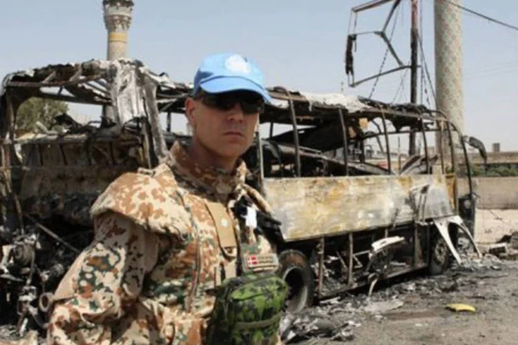Observador da ONU inspeciona ônibus incendiado em Damasco, onde o exército realiza operações (Louai Beshara/AFP)