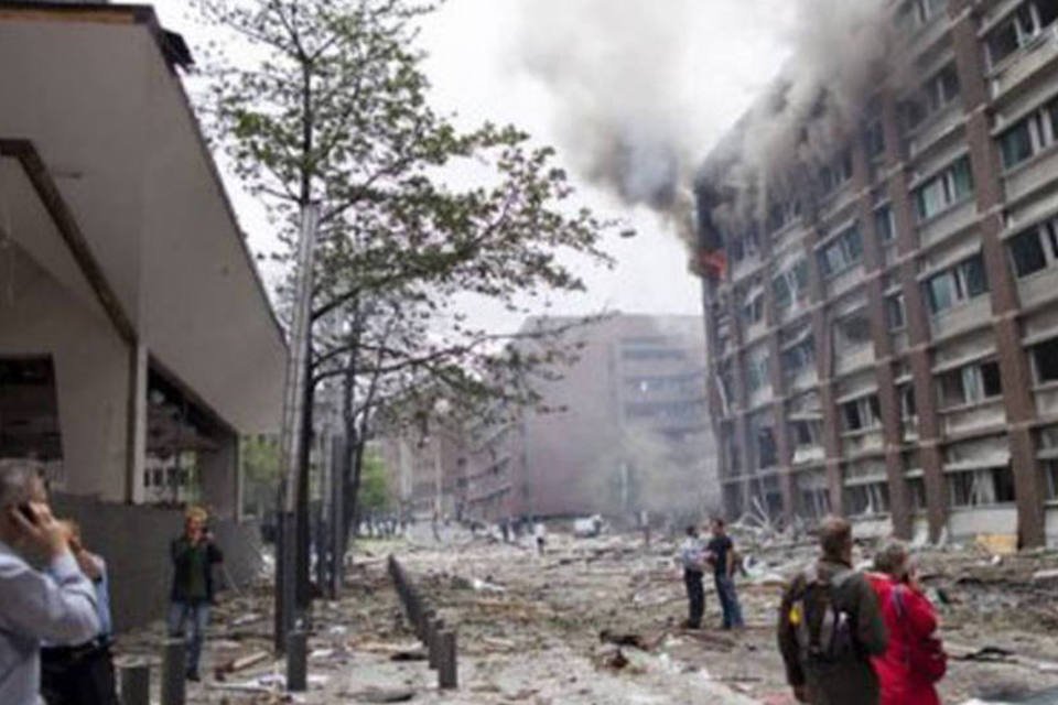 Chamas e fumaça saem de uma coluna do prédio sede do Governo norueguês, em Oslo, destruído com a explosão (Thomas Winje/AFP)