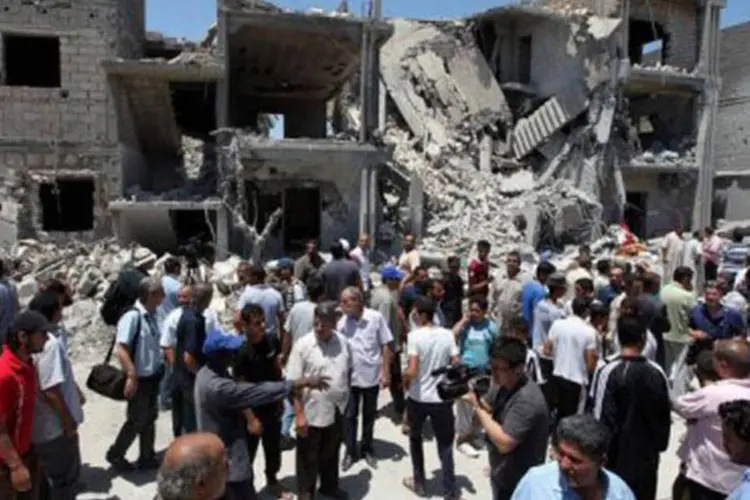 Jornalistas e moradores observam destroços após bombardeios da Otan em Arada, segundo informações do governo líbio
 (Mahmud Turkia/AFP)