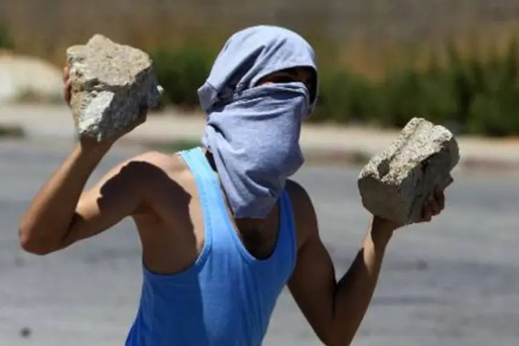 Manifestante palestino carrega pedras durante um confronto com tropas israelenses (Abbas Momani/AFP)