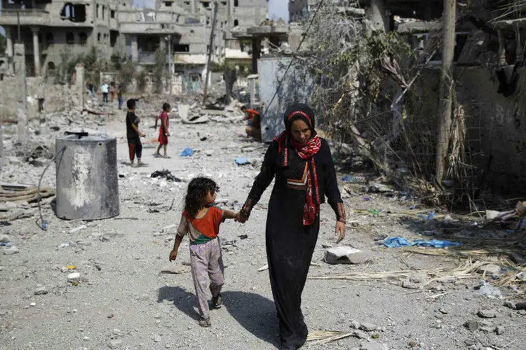 
	Palestina caminha com crian&ccedil;a por pr&eacute;dios destru&iacute;dos ao norte da Faixa de Gaza
 (Finbarr OReilly/Reuters)