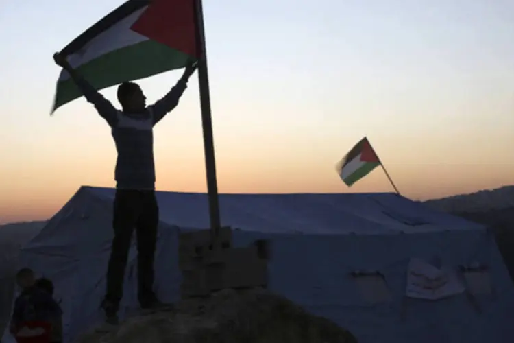 Ativista segura bandeira palestina perto de uma tenda recém montada no vilarejo de Beit Iksa, na Cisjordânia, entre Ramallah e Jerusalém
 (Mohamad Torokman/Reuters)