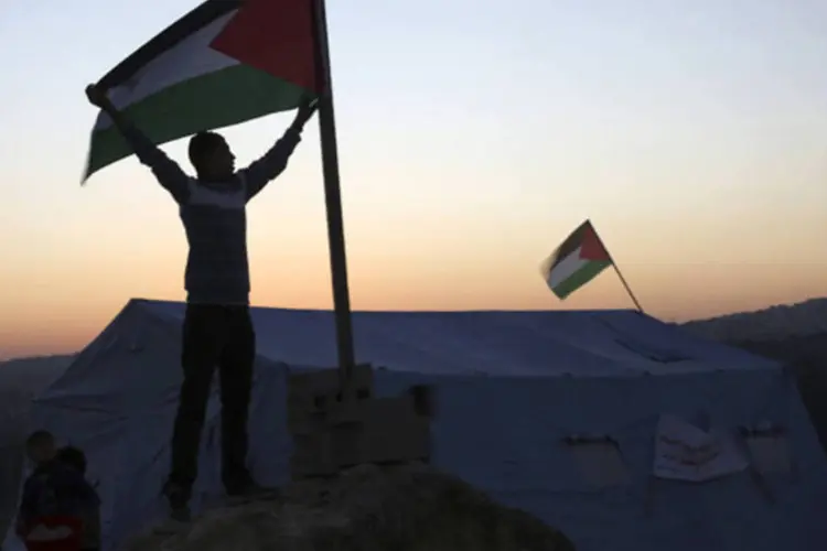 
	Ativista segura bandeira palestina: &quot;Esta terra &eacute; nossa, e n&oacute;s somos contra a coloniza&ccedil;&atilde;o e a ocupa&ccedil;&atilde;o apoiada pelo governo dos Estados Unidos&quot;, afirmou um dos organizadores.
 (Mohamad Torokman/Reuters)