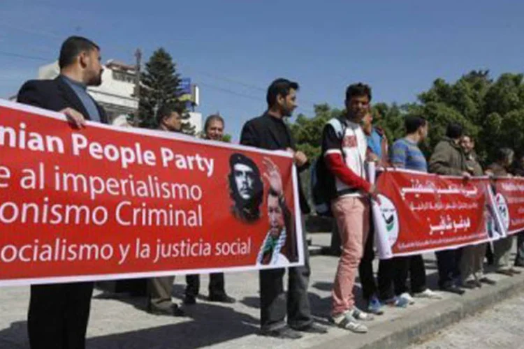 
	Palestinos exibem faixas com a imagem de Ch&aacute;vez, em Gaza: Ch&aacute;vez tamb&eacute;m expulsou o embaixador israelense e rompeu as rela&ccedil;&otilde;es diplom&aacute;ticas com o pa&iacute;s.
 (©afp.com / Mohammed Abed)